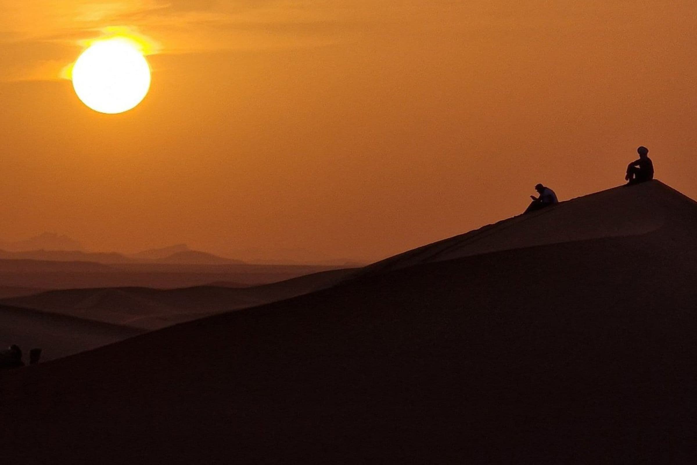 Caravane de dromadaires traversant les dunes de Merzouga au coucher du soleil
