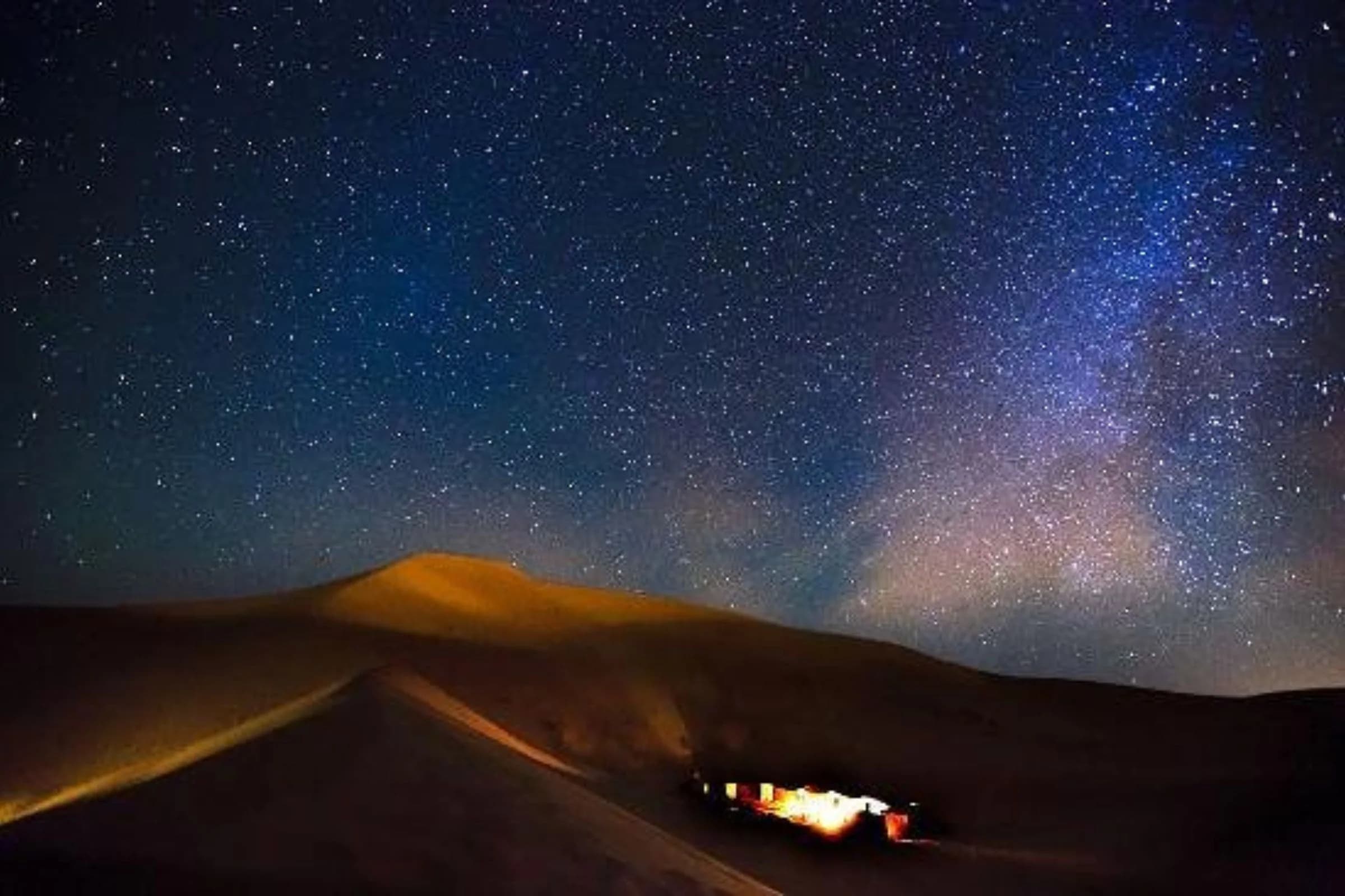 Main tenant un smartphone avec une application de voyage devant les dunes